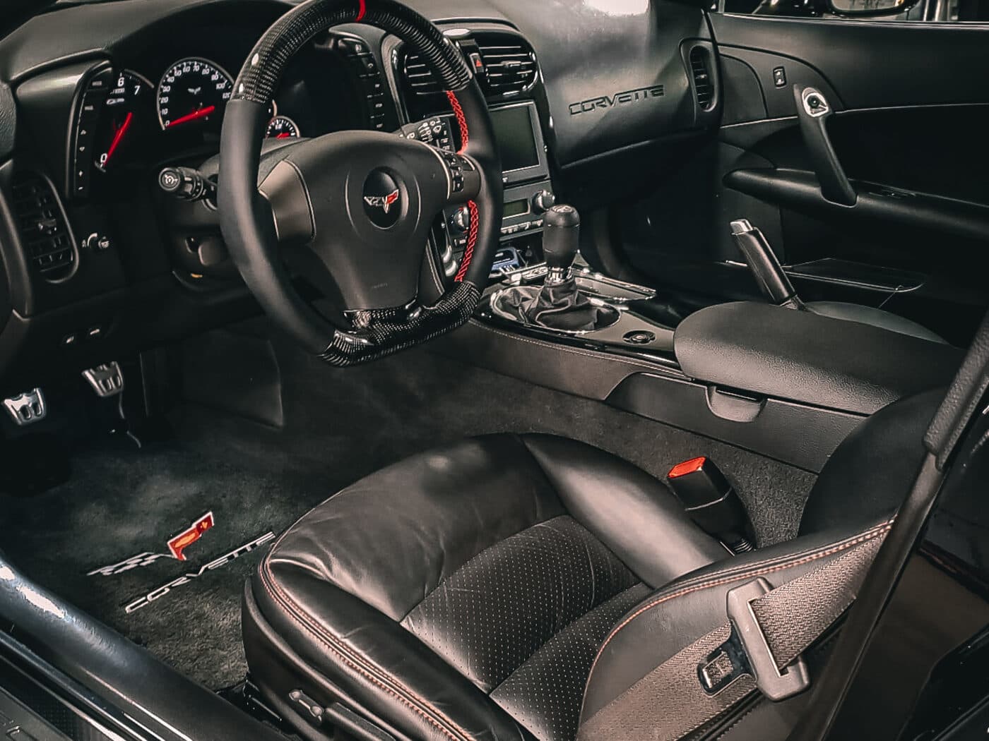 The interior of a sports car in a Handled service bay, driver's door open