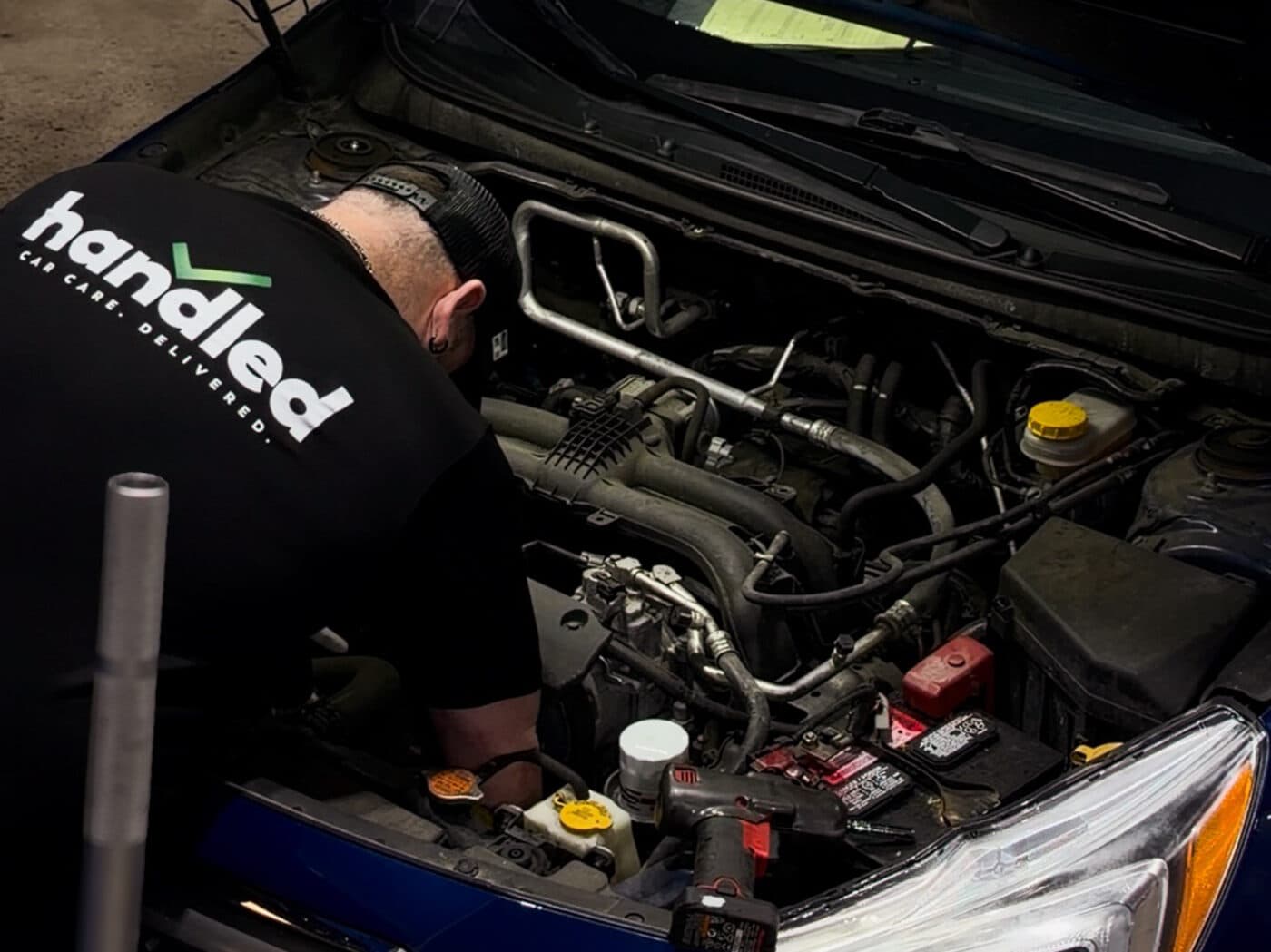 A Handled automotive technician at work under the hood of a car